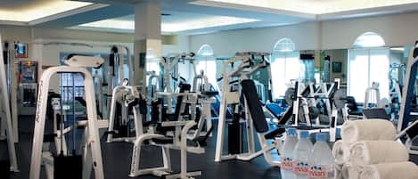 A gym with various exercise machines, towels, and bottled water.