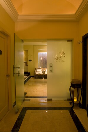 A hotel corridor with a spa sign, a bed, and a reception area.