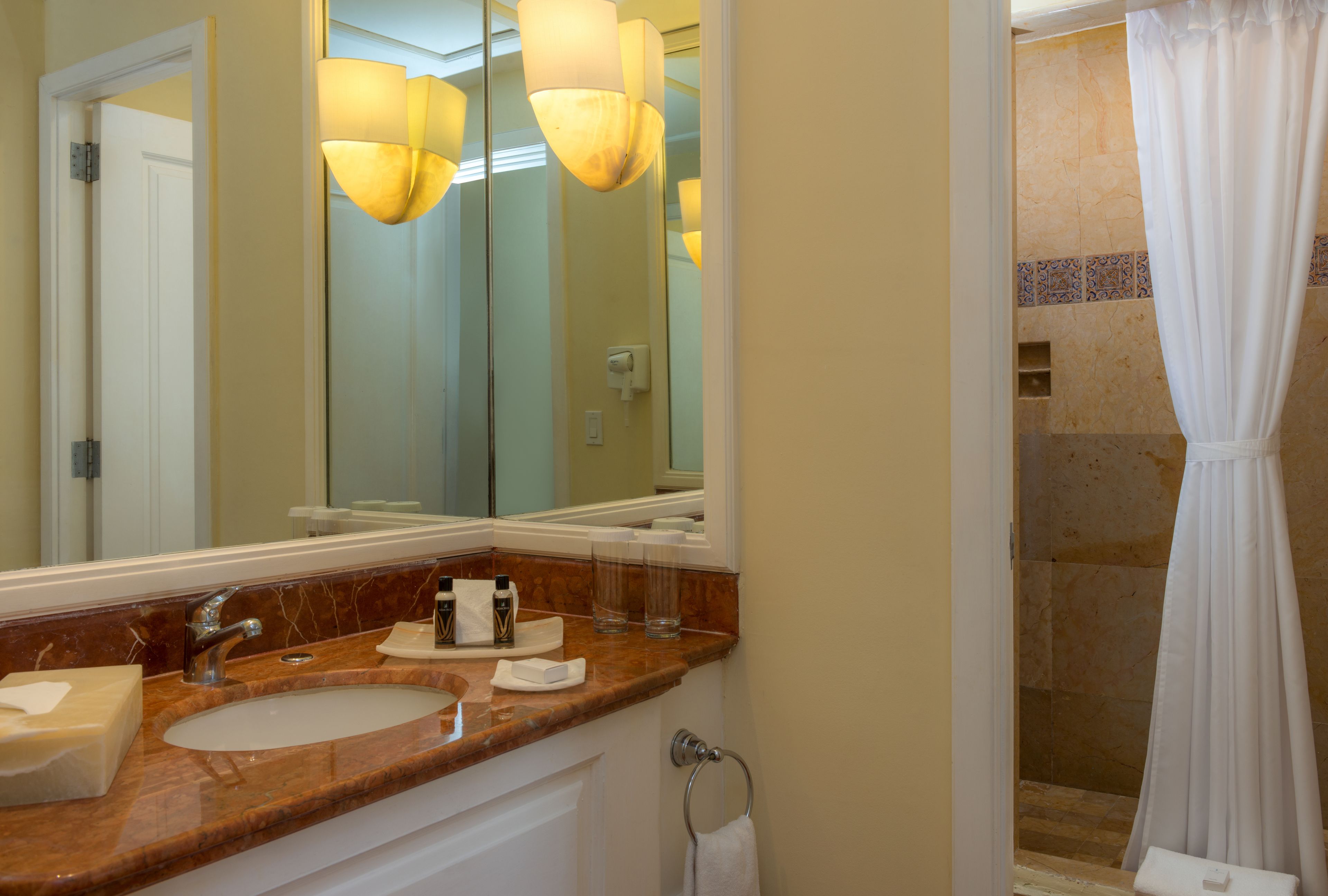 A bathroom with two sinks, a large mirror, and a shower area with a curtain.