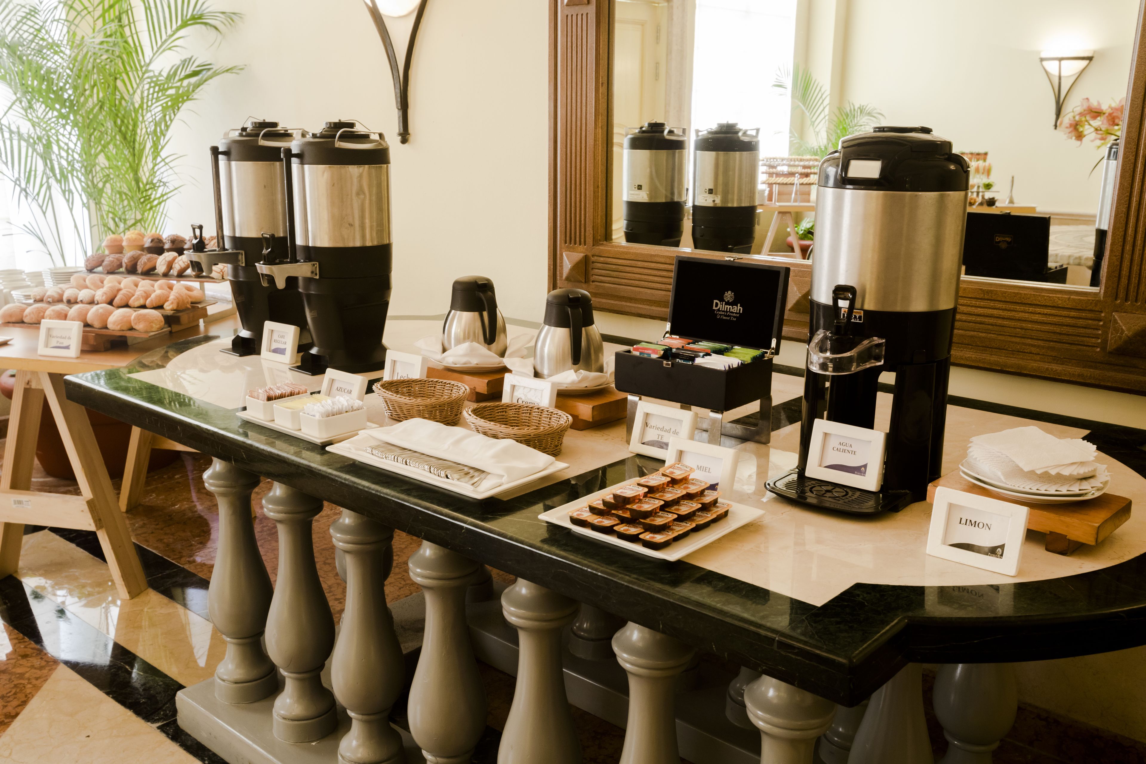 A buffet setup with coffee machines, a variety of pastries, and labeled food items.