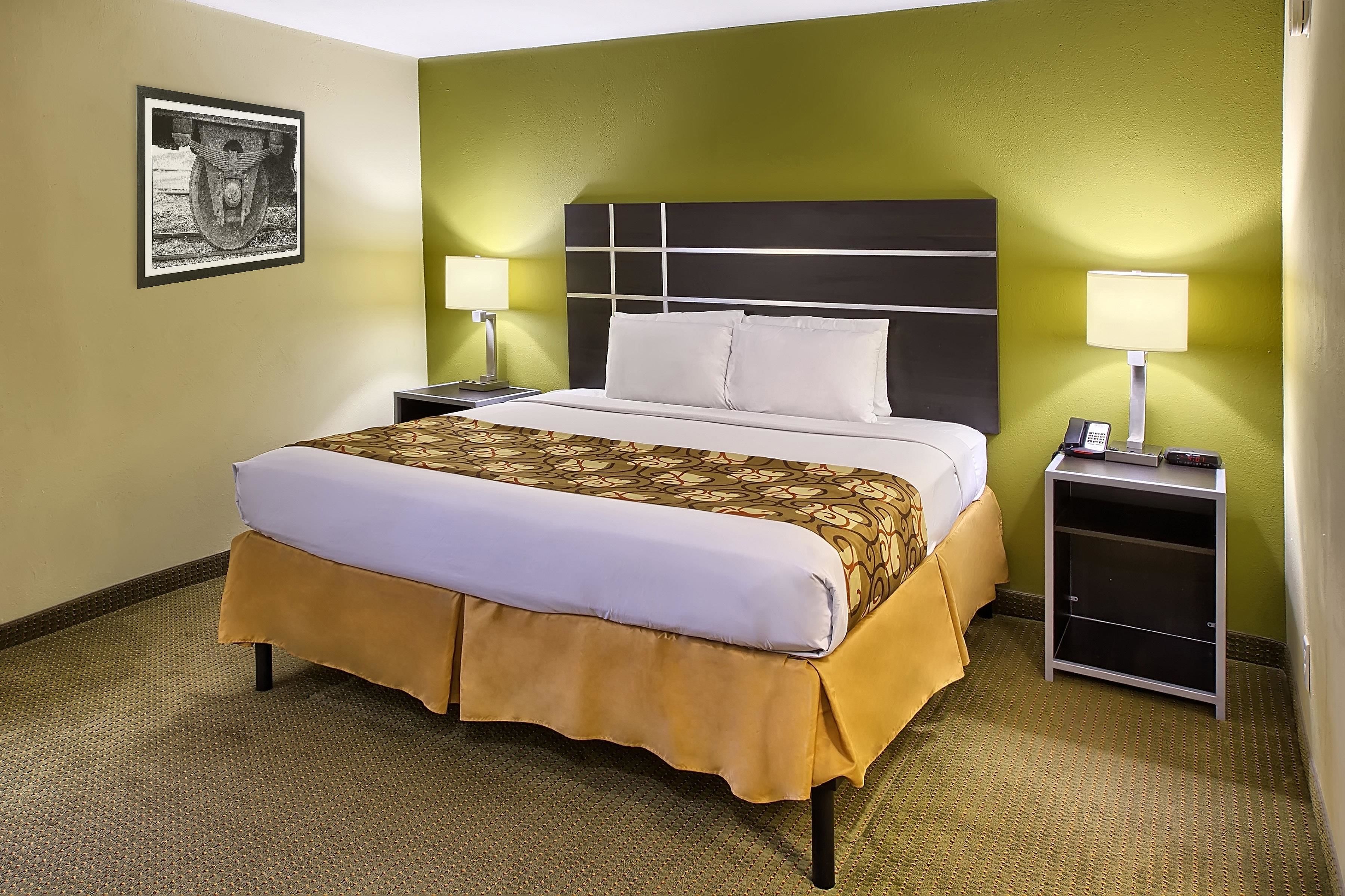 A hotel room with a large bed, two bedside tables with lamps, and a framed picture on the wall.
