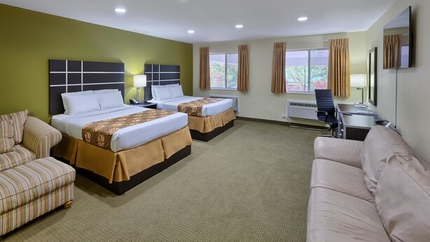 A hotel room with two beds, a sofa, a desk, and a TV. - Country Hearth Inn Knightdale Raleigh (Knightdale)
