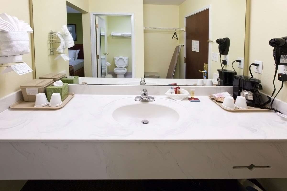 Une salle de bain d’hôtel avec un grand lavabo, un porte-serviettes et un sèche-cheveux.