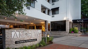 Exterior del Hotel Andrew, con fachada de piedra, un cartel que indica la dirección y un restaurante cercano llamado Colby.