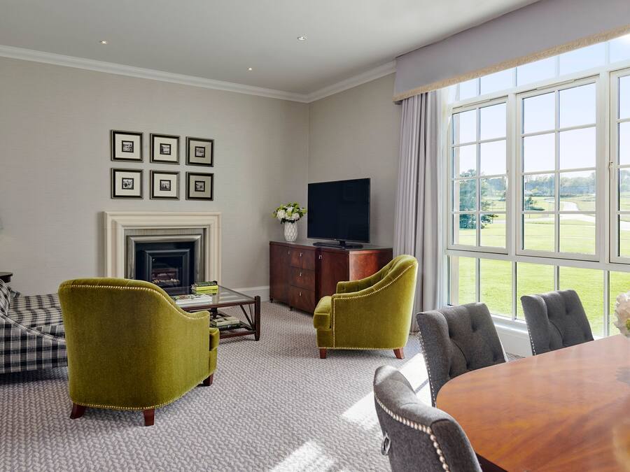 A spacious living room with a fireplace, a television, and a large window offering a view of the outdoors.