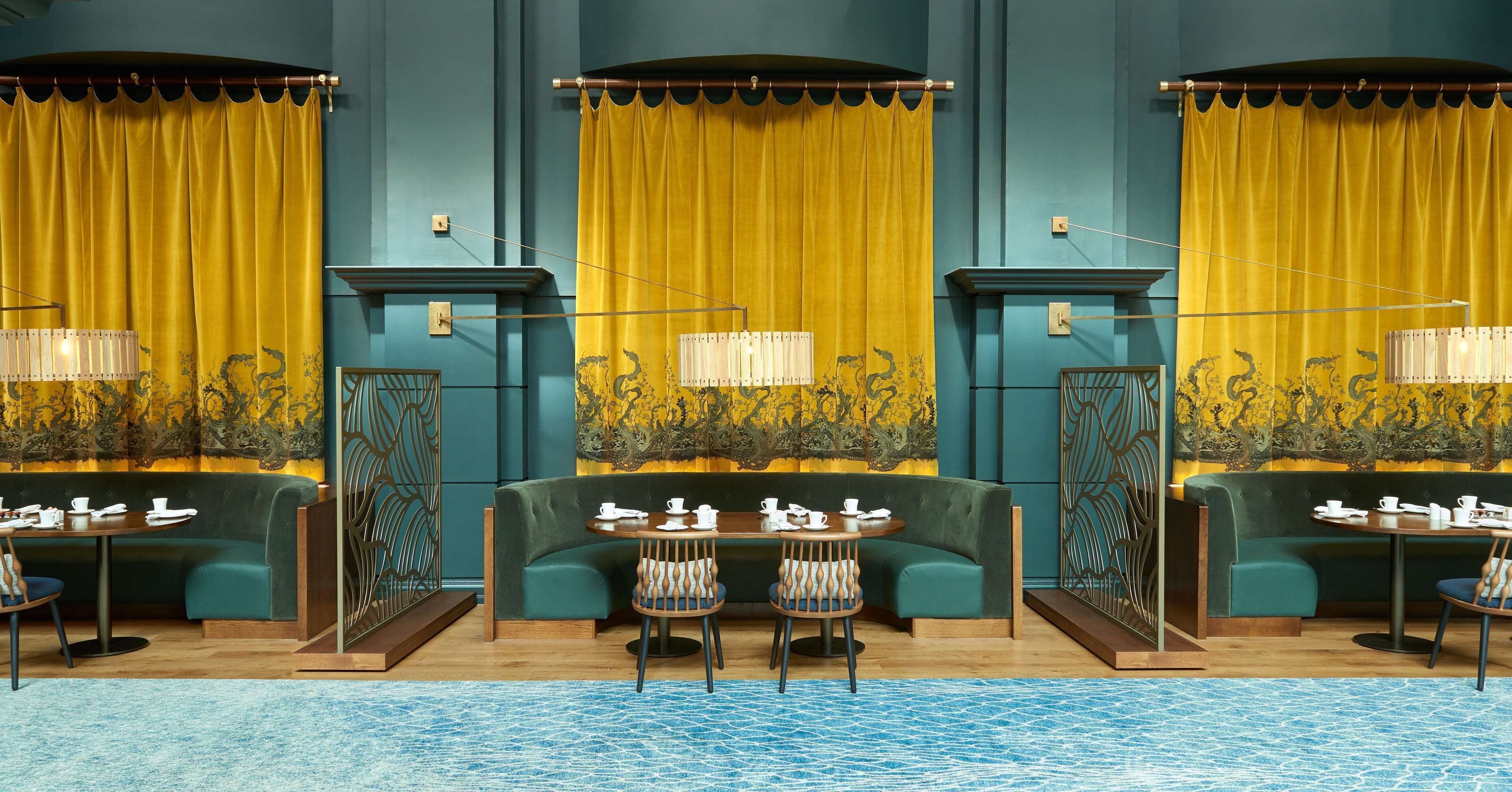 Un interior moderno con sofás color turquesa, cortinas amarillas y una zona de piscina.
