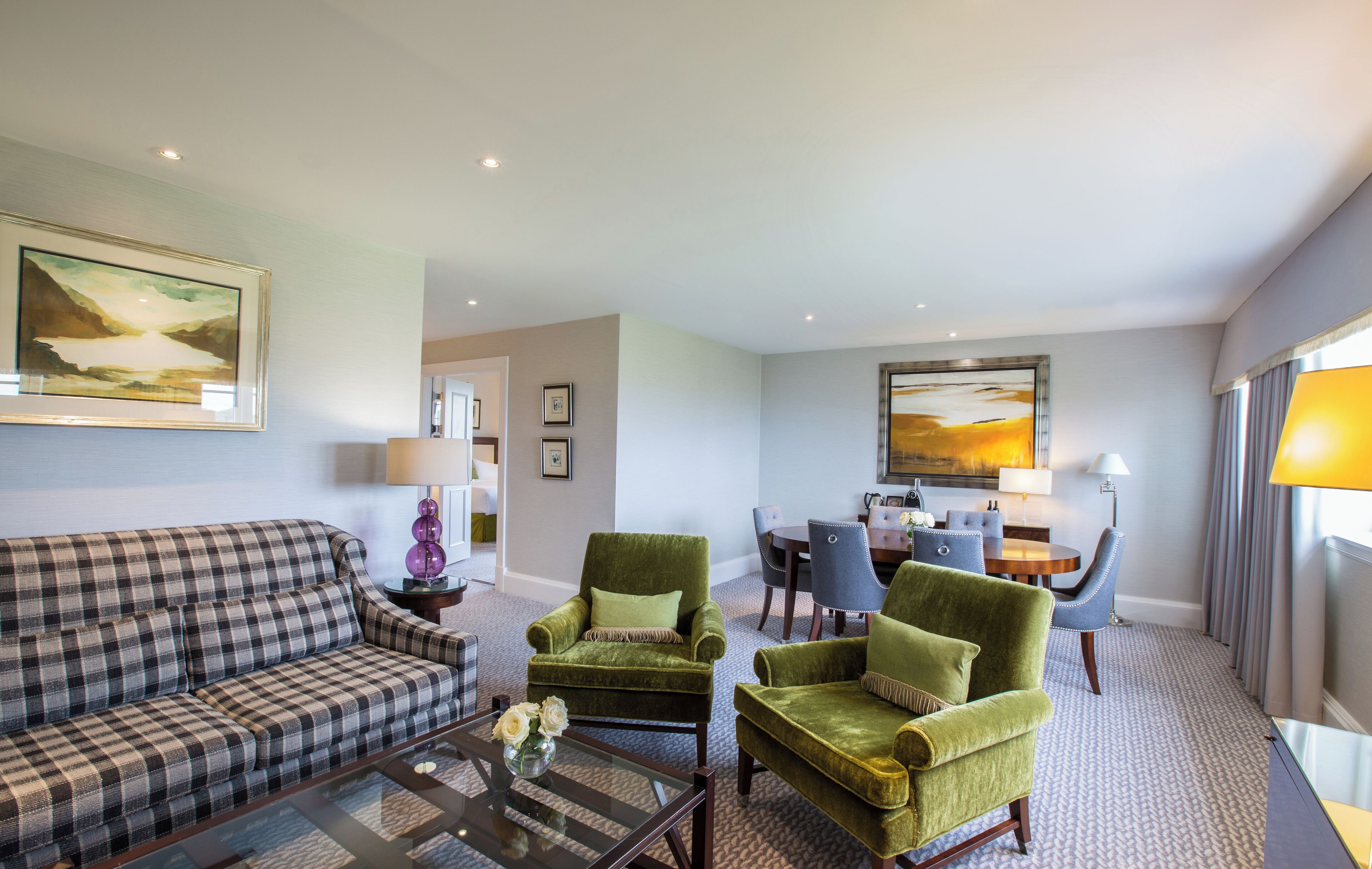 A modern living room with a sofa, armchairs, a coffee table, and a dining area with chairs and a table.