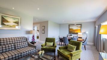 A modern living room with a sofa, armchairs, a coffee table, and a dining area with chairs and a table.