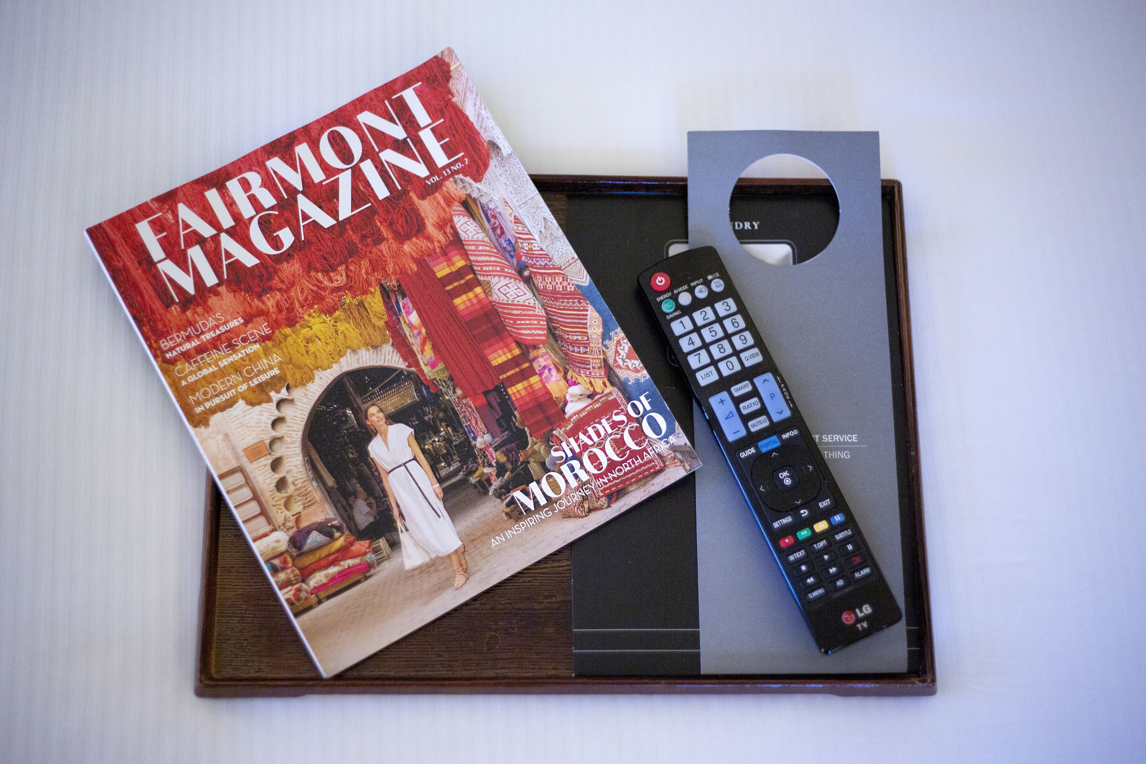 En tidning med titeln ”Fairmont Magazine” och en fjärrkontroll på ett brickbord.