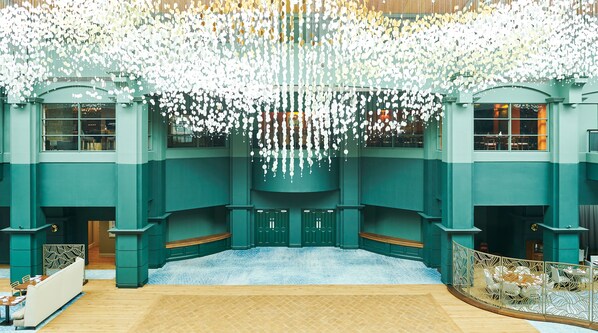 A spacious atrium with a high ceiling adorned with hanging spherical decorations, a central seating area with benches, and a patterned floor. - Fairmont St Andrews (St. Andrews)