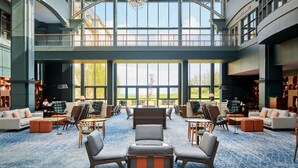 A spacious lobby with a high ceiling, large windows offering a view of the outdoors, and a variety of seating arrangements including sofas and chairs. - Fairmont St Andrews (St. Andrews)