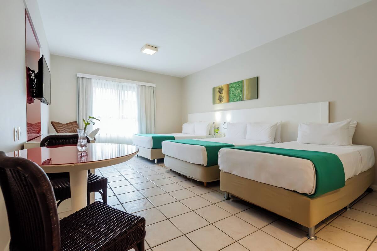 Een hotelkamer met twee bedden, een eettafel en een televisie.