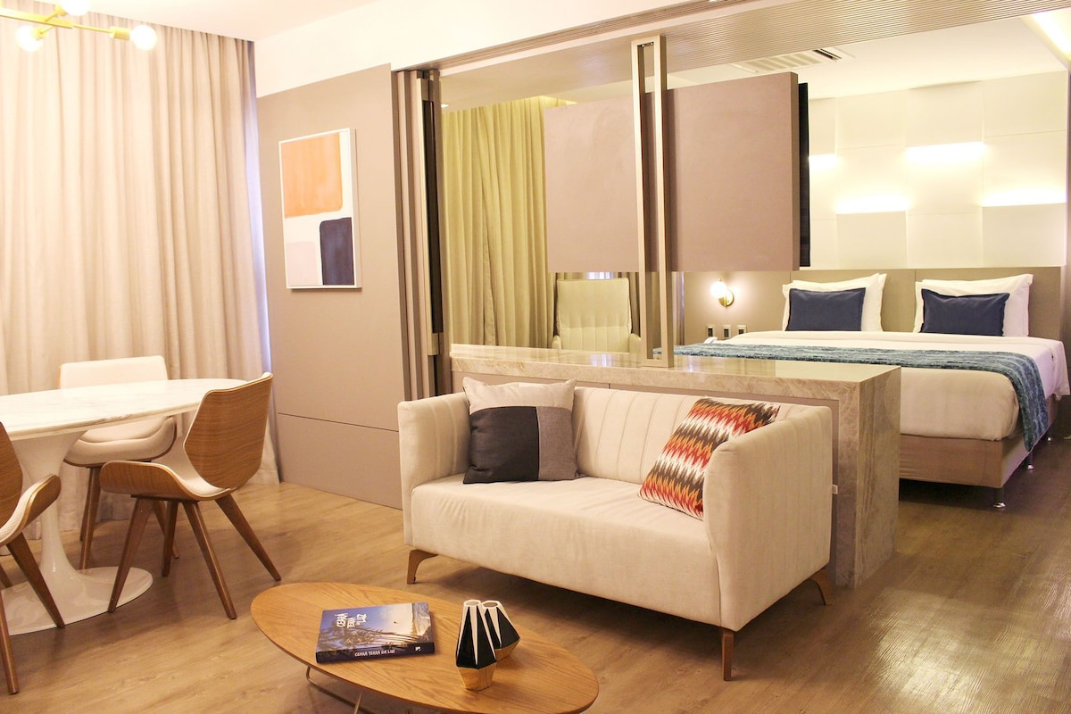 A hotel room with a bed, a sofa, a desk, and a chair.
