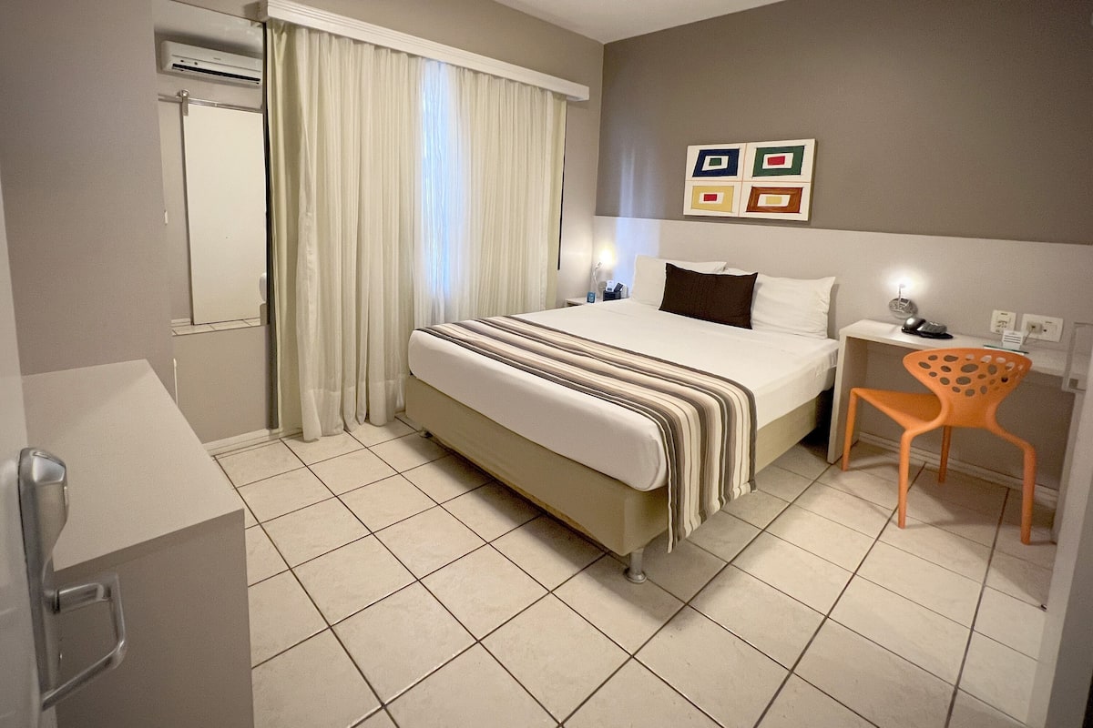 Een hotelkamer met een bed, een stoel, een bureau en een badkamer.