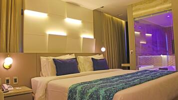 Habitación de hotel con cama, mesita de noche con teléfono y espejo.