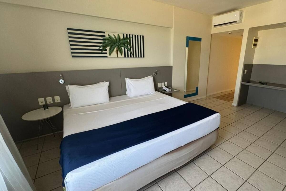 Een hotelkamer met een groot bed, nachtkastjes, een spiegel en een klein bureau.