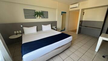 Una camera d'albergo con un letto grande, comodini, uno specchio e una piccola scrivania.