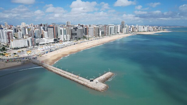 Un paisaje urbano costero con rascacielos, una playa arenosa y un mar tranquilo.
