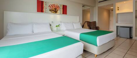 A hotel room with two beds, a small table with a plant, a chair, and a TV.