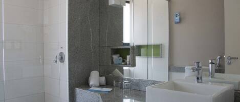 Un baño moderno con cabina de ducha, un lavabo grande y un espejo.