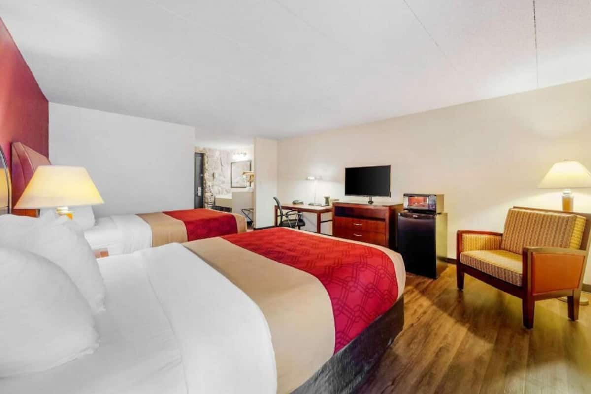 Een hotelkamer met twee bedden, een bureau, een televisietoestel en een stoel.