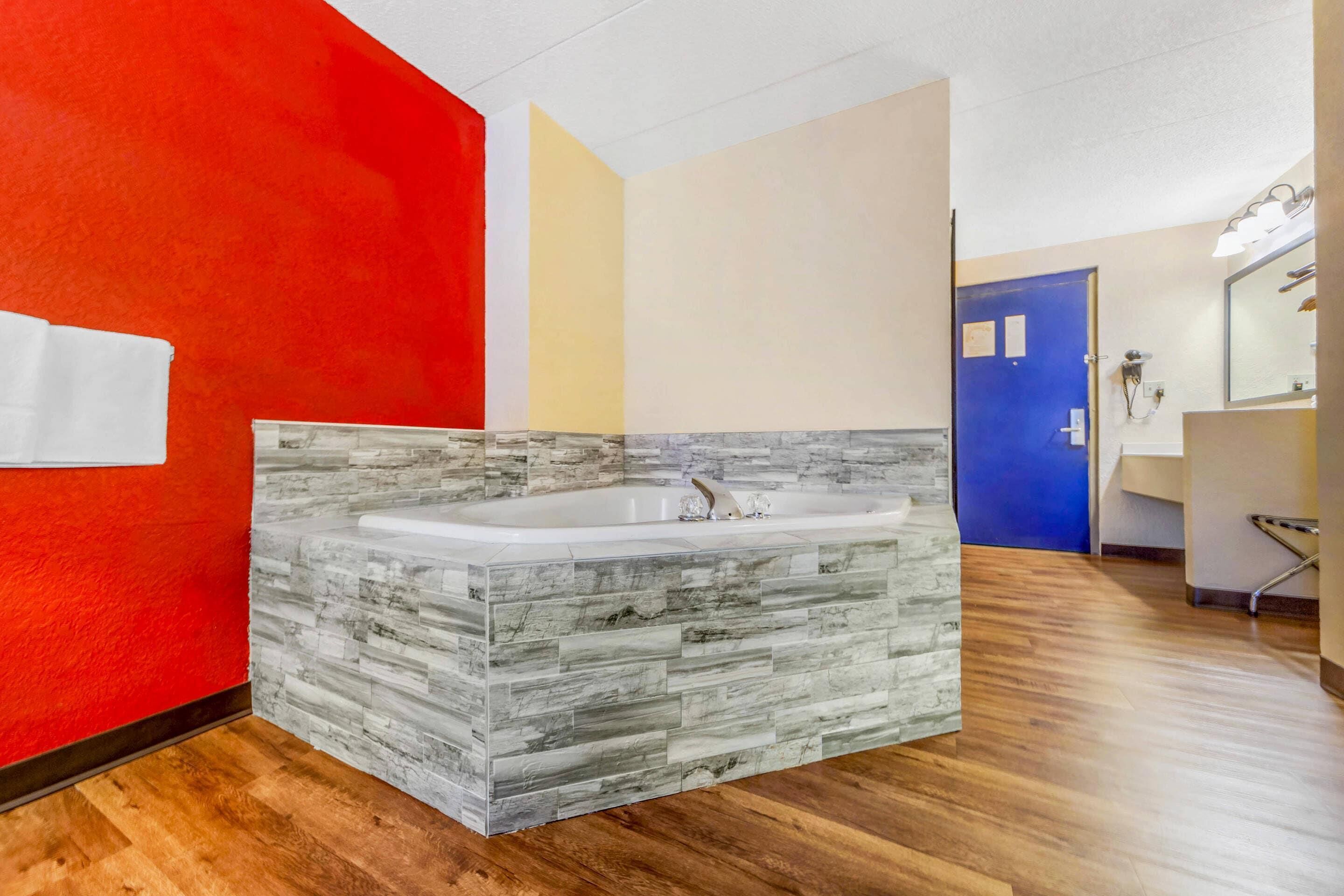 A bathroom with a stone-textured vanity, a white bathtub, and a blue door.