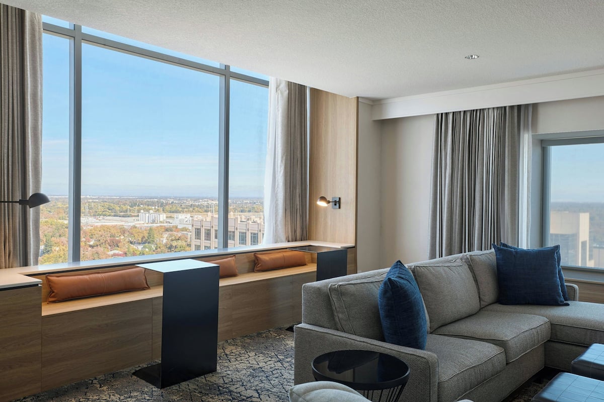 Ein modernes Wohnzimmer mit großem Fenster, einer Couch, einem Couchtisch und einer eingebauten Bank mit Kissen.