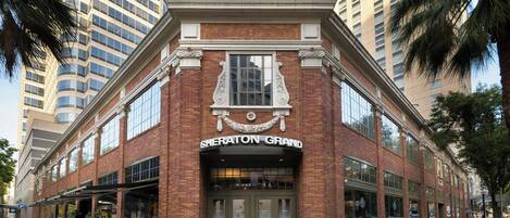 A brick building with a large arched entrance and a sign reading 'Sheraton Grand'.
