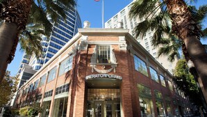 Un hôtel Sheraton Grand à la façade en briques, doté de grandes fenêtres et bordé de palmiers.