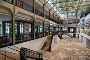 Un atrium à plusieurs niveaux, doté d’un escalier central, de rampes en verre et d’un sol à motifs.