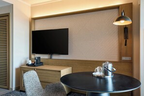 Relax in a stylish room with a flat-screen TV, coffee maker, and comfortable chair.