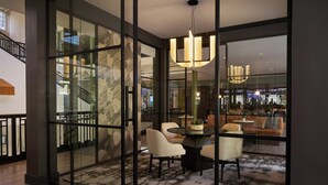 Un intérieur moderne avec des cloisons en verre, un escalier, un coin repas avec des chaises et une table, et un luminaire suspendu.
