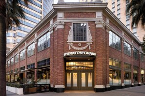 A Sheraton Grand hotel with a classic brick facade, large windows, and a prominent entrance.