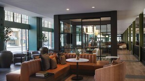 Un espace de détente moderne avec des canapés en cuir, des tables rondes et de grandes fenêtres.