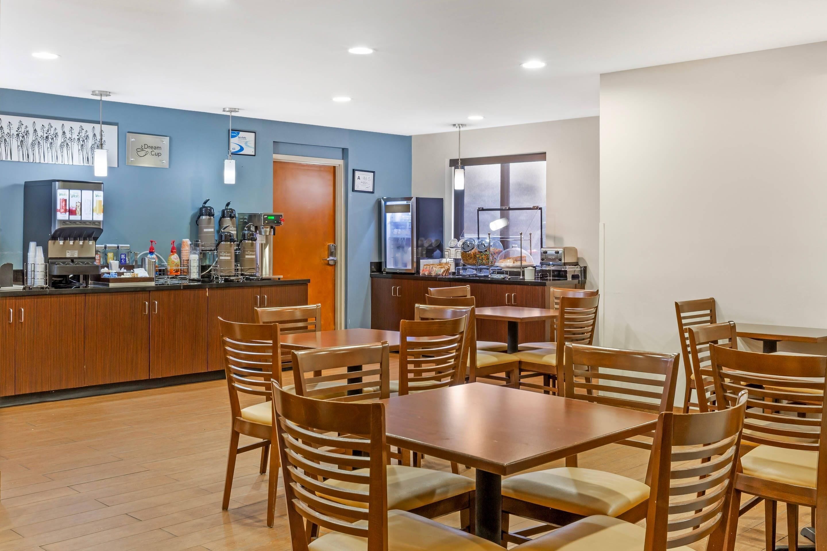 A restaurant with wooden tables and chairs, a coffee machine, and a refrigerator.
