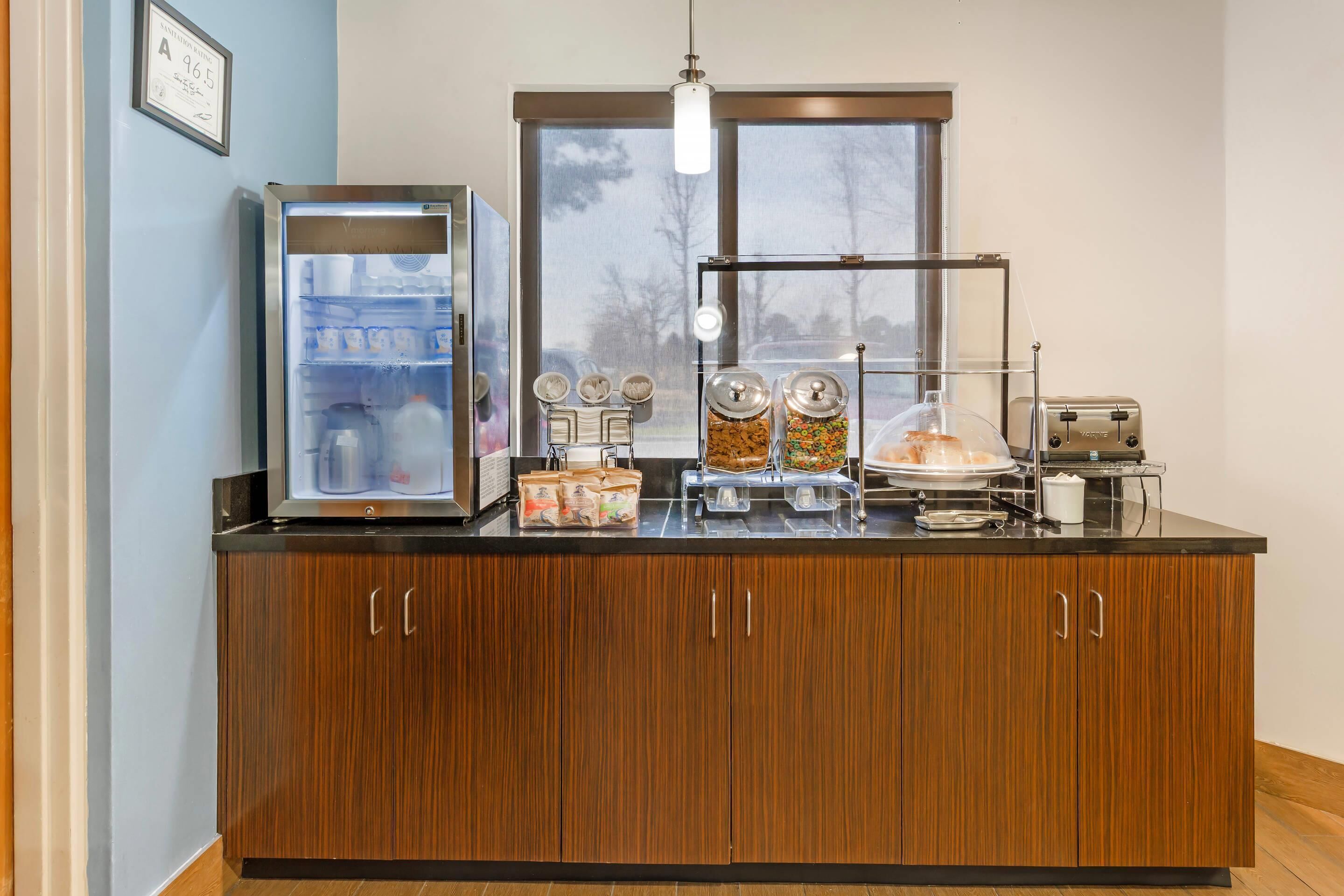 A kitchen area with a refrigerator, a window, a toaster, and various food dispensers.