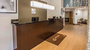 A reception area with a wooden reception desk, a sign reading "Sleep Inn," and a mural of trees on the wall. - Sleep Inn Greensboro Airport (Greensboro)