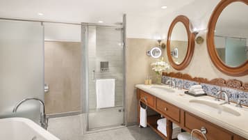 Un baño moderno con cabina de ducha de vidrio, un mueble de tocador grande con lavamanos dobles y dos espejos montados en la pared.