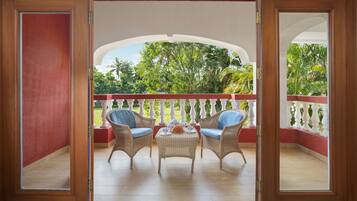 Relax on the balcony overlooking a serene garden with lush trees and plants, featuring two comfortable chairs and a small table.
