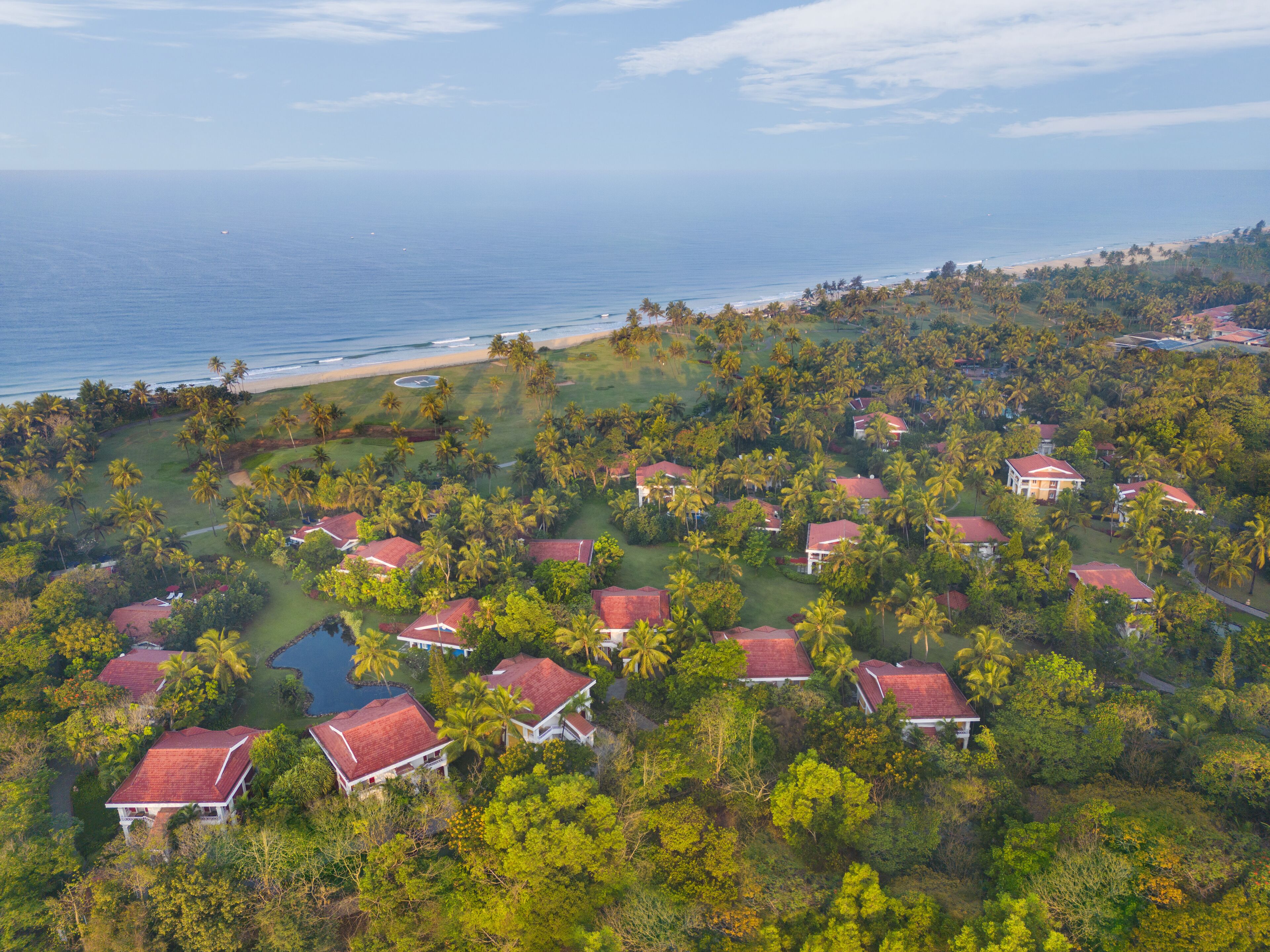 An aerial view of a resort with multiple buildings, a beach, and palm trees.