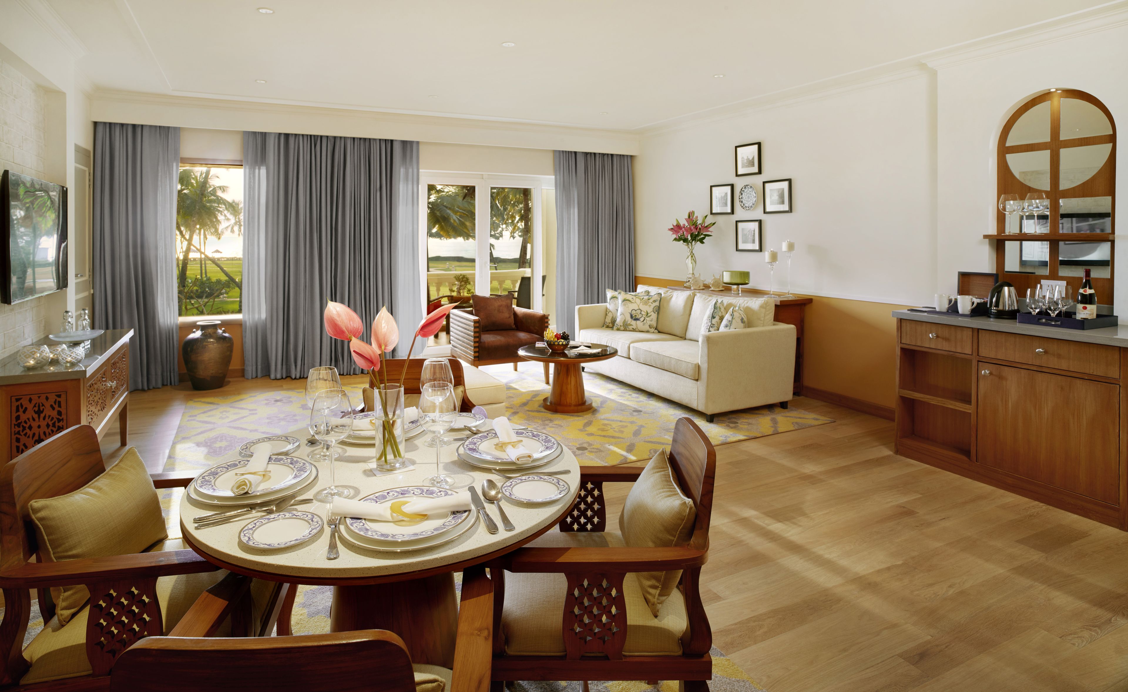A dining area with a round table set for six, surrounded by wooden chairs.