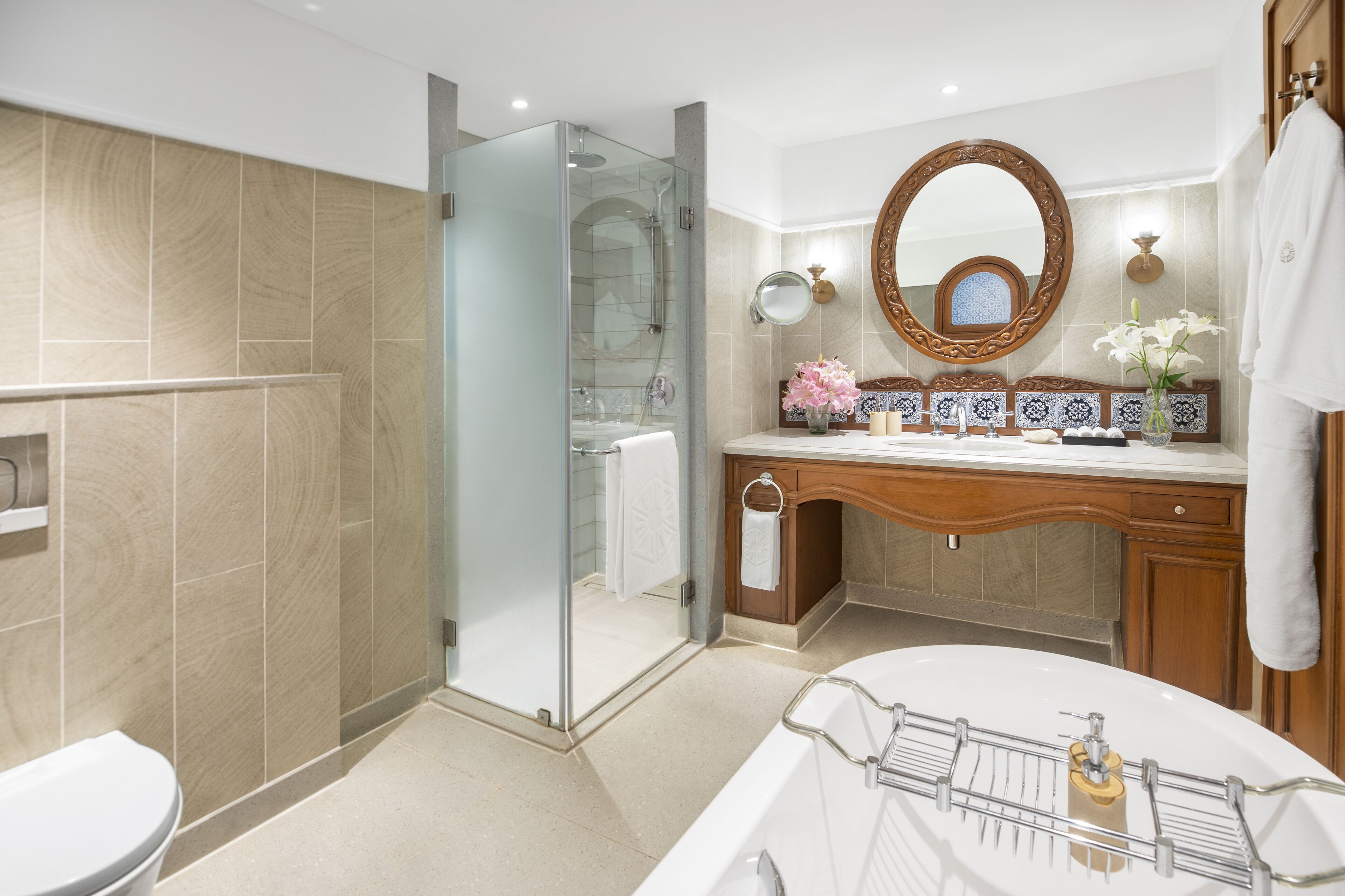 Un baño moderno con ducha de vidrio, una bañera independiente y un tocador de madera con un espejo grande.