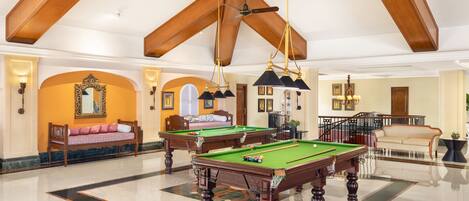 A spacious room with a pool table, a sofa, and a staircase leading to another level.