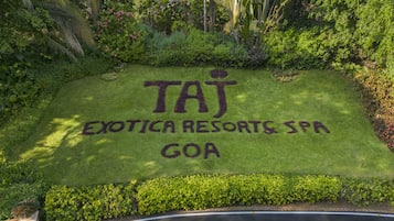 A sign for Taj Exotica Resorts & Spa in Goa, surrounded by lush greenery.