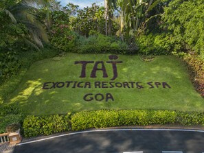 A sign for Taj Exotica Resorts & Spa in Goa, surrounded by lush greenery. - Taj Exotica Resort & Spa, Goa (Benaulim)