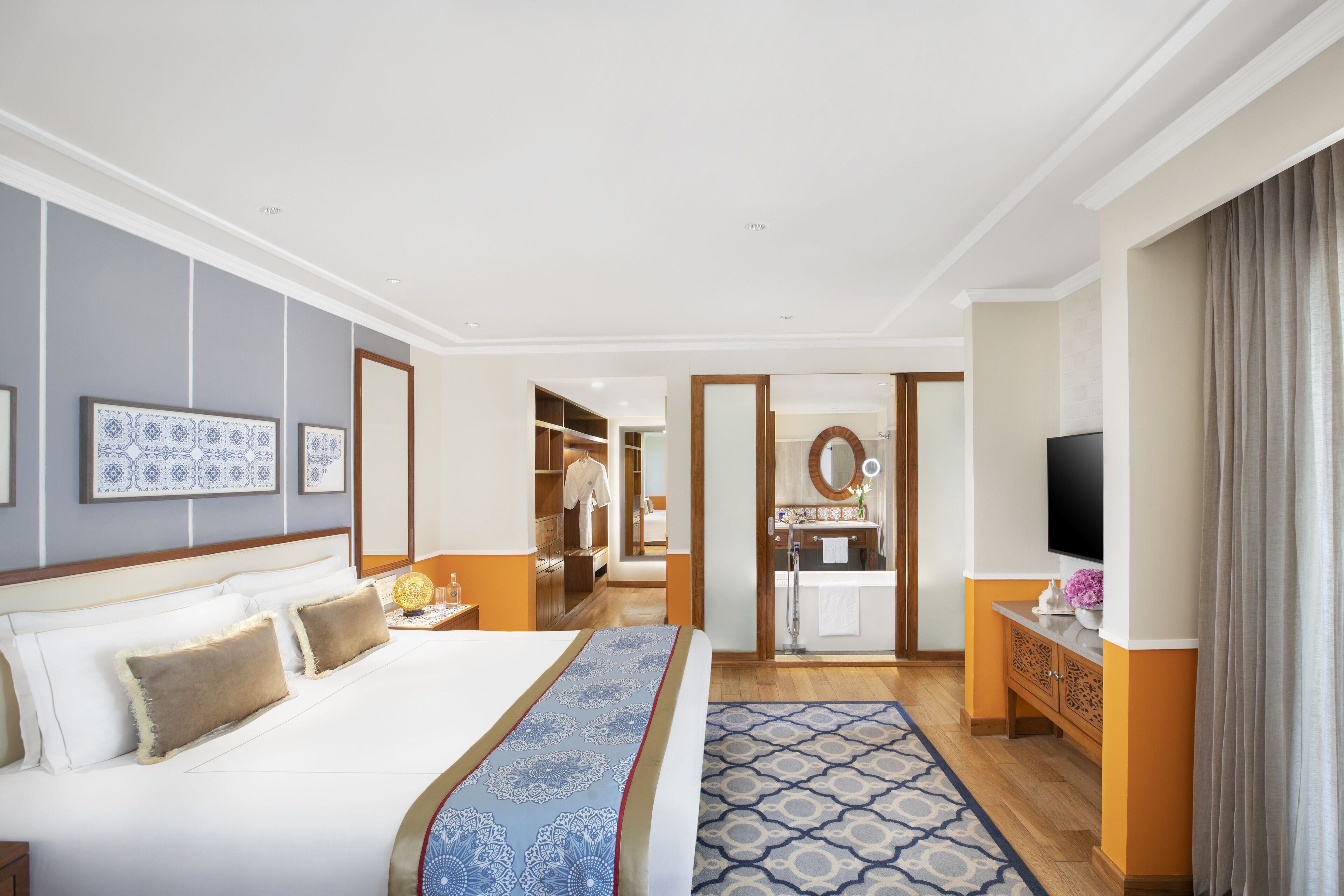 Een hotelkamer met een groot bed, een televisie, een badkamer en een inloopkast.