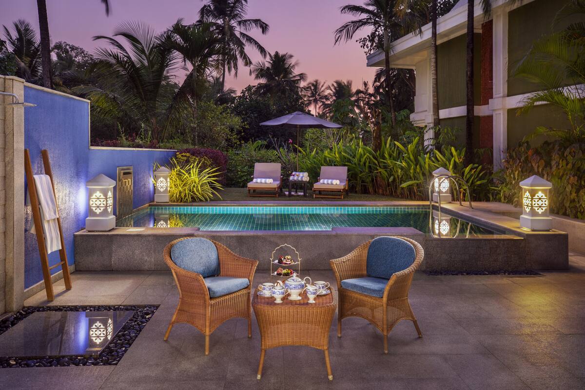 Un área junto a la piscina con sillones de descanso, una mesa con teteras y faroles decorativos.