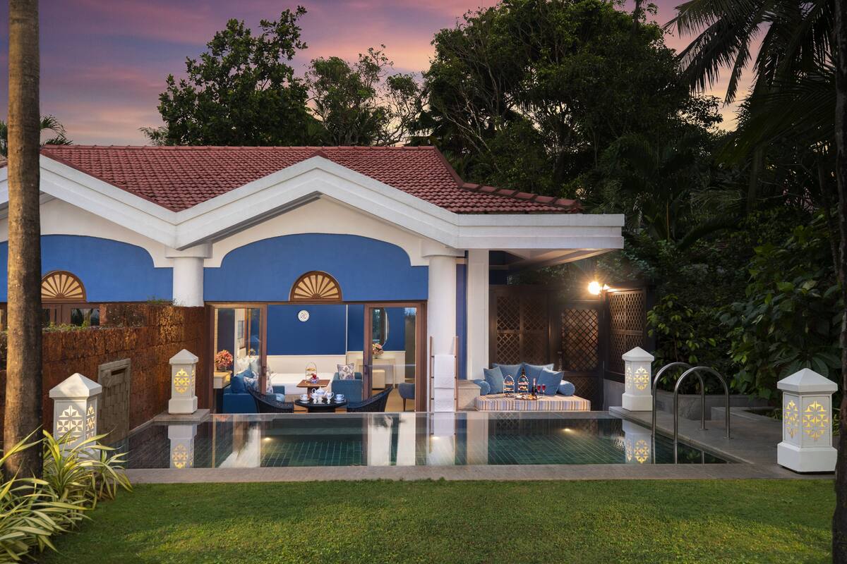 Una casa moderna con piscina, fachada azul y blanca, y un patio con mobiliario exterior.