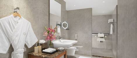 A modern bathroom with a marble vanity, a large mirror, a toilet, and a shower area.