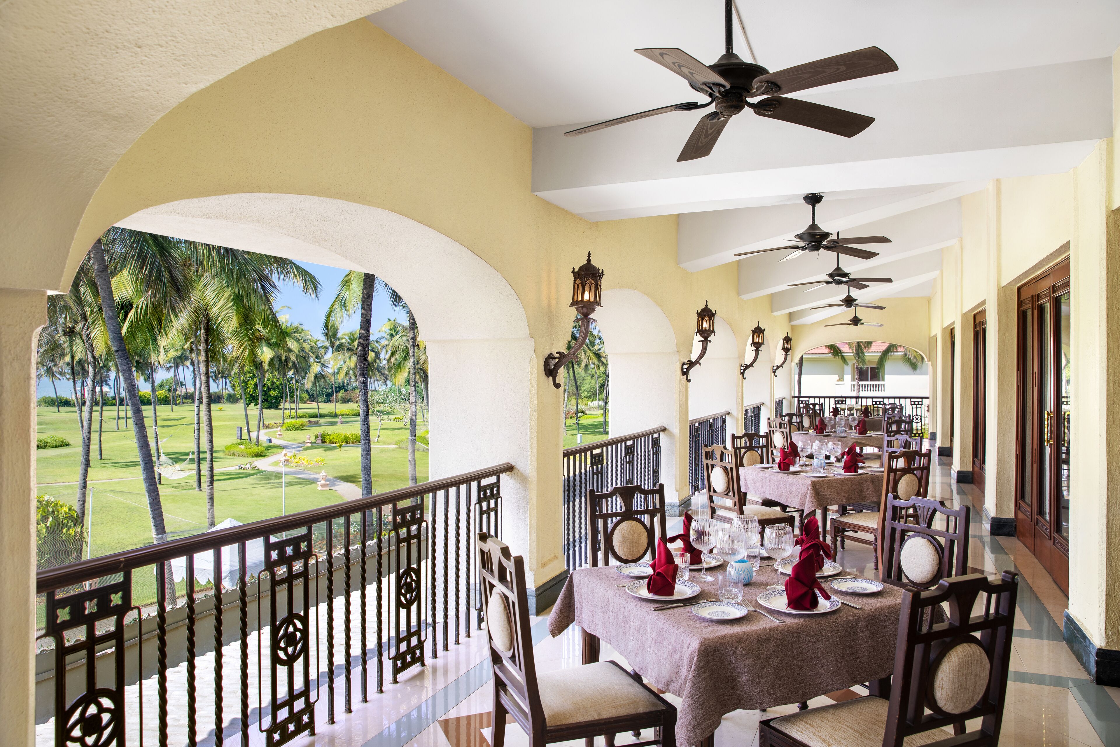 A dining area with tables set for a meal, overlooking a golf course.